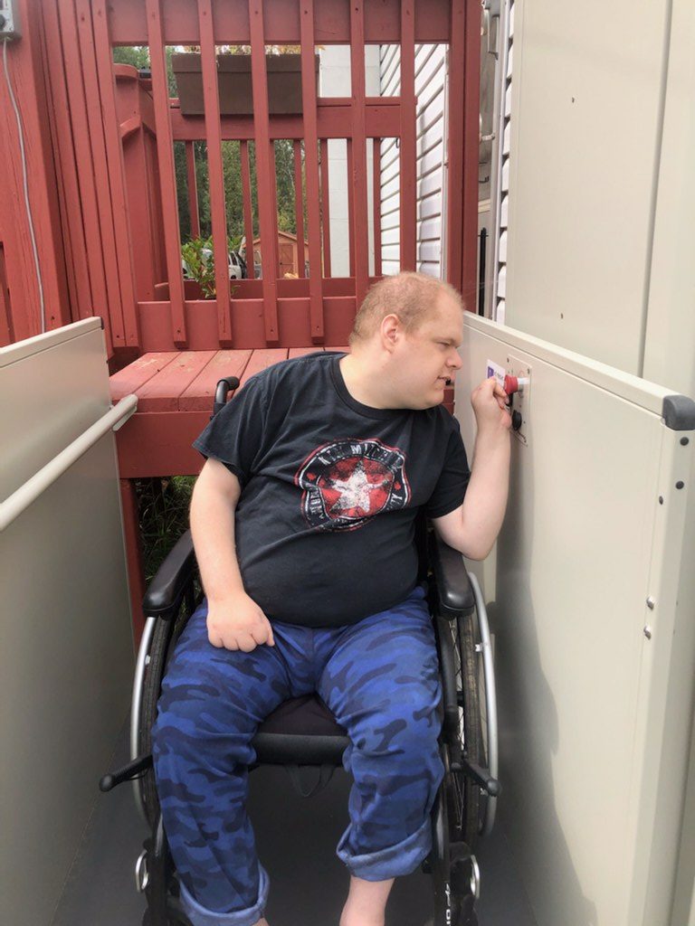 A man in a wheelchair is looking to the left side and pressing a red button.