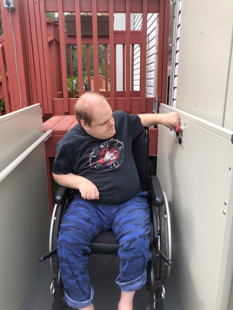 A man in a wheelchair is looking slightly to the left side and pressing a red button.