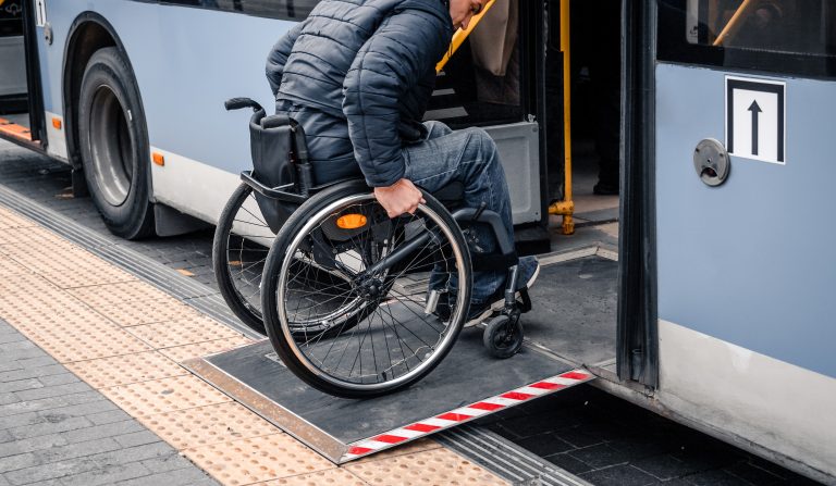 Person with a physical disability enters public transport with an accessible ramp